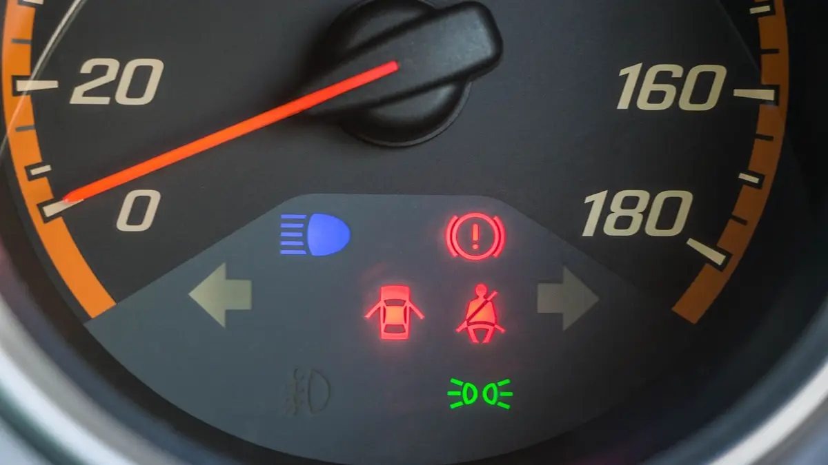 Tableau de bord d’une voiture avec voyant moteur orange allumé et conducteur inquiet au volant